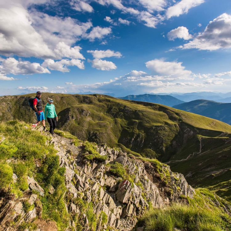 Zwei Wanderer auf einem Berggrat mit Blick auf eine atemberaubende Landschaft